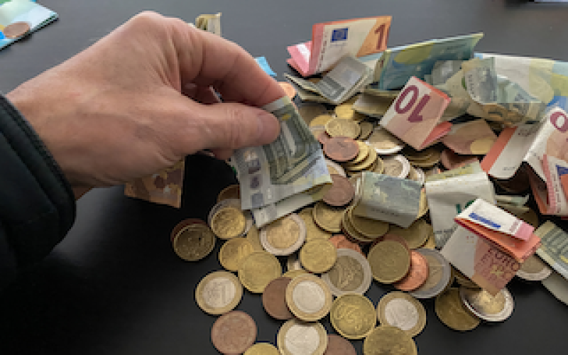 Cash income controls image of hand touching cash notes and coins